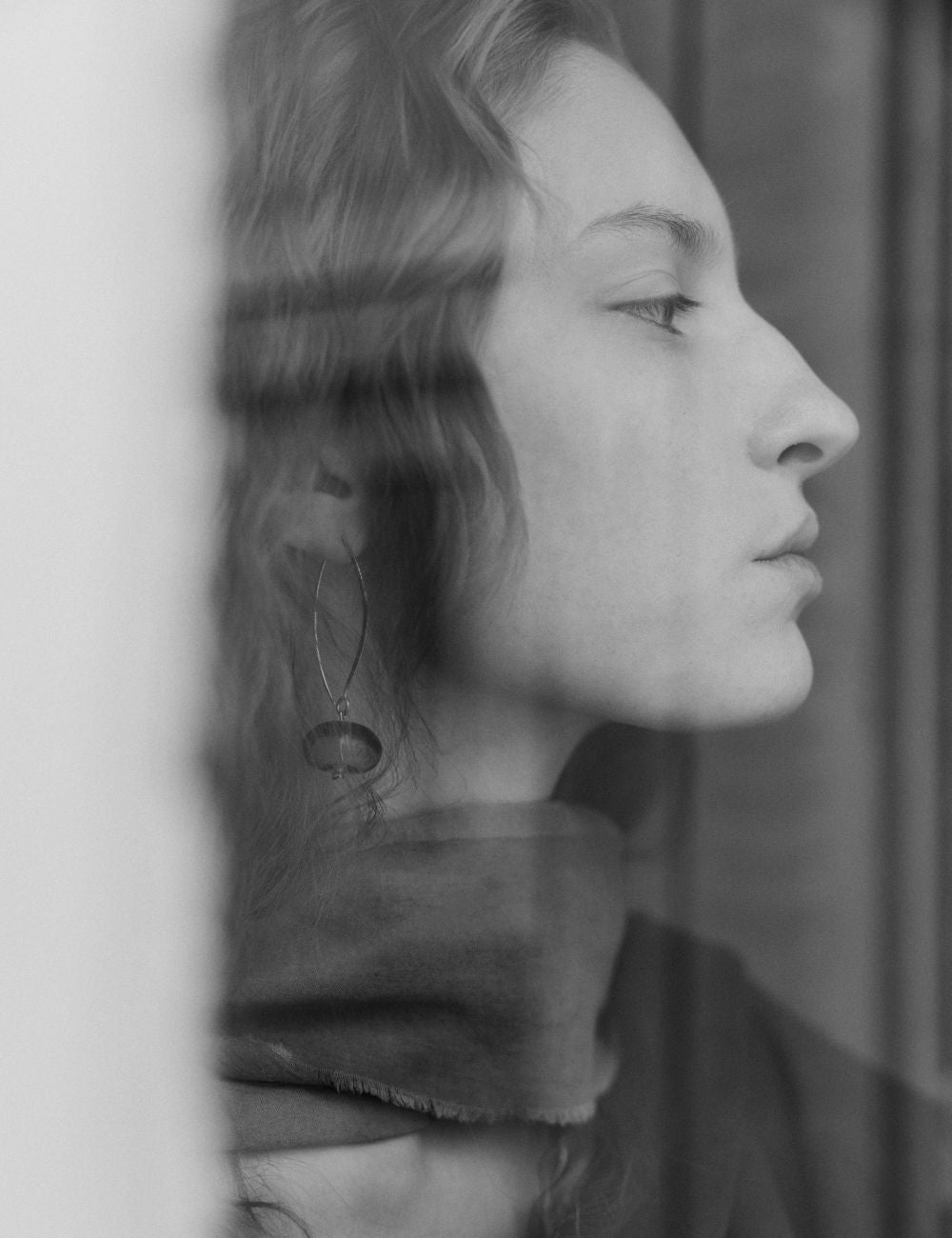 Black and white photo of a girl with long hair in window reflection