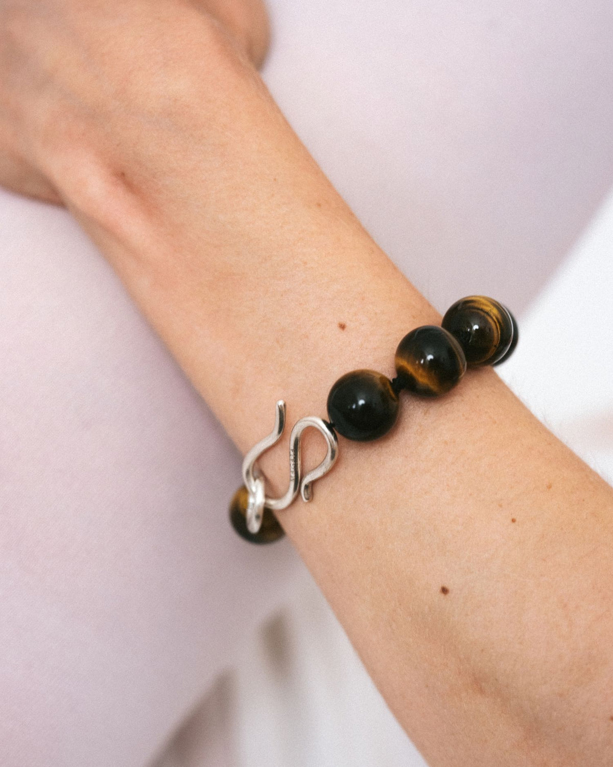Brown tiger-eye beaded bracelet on wrist with silver S-hook clasp