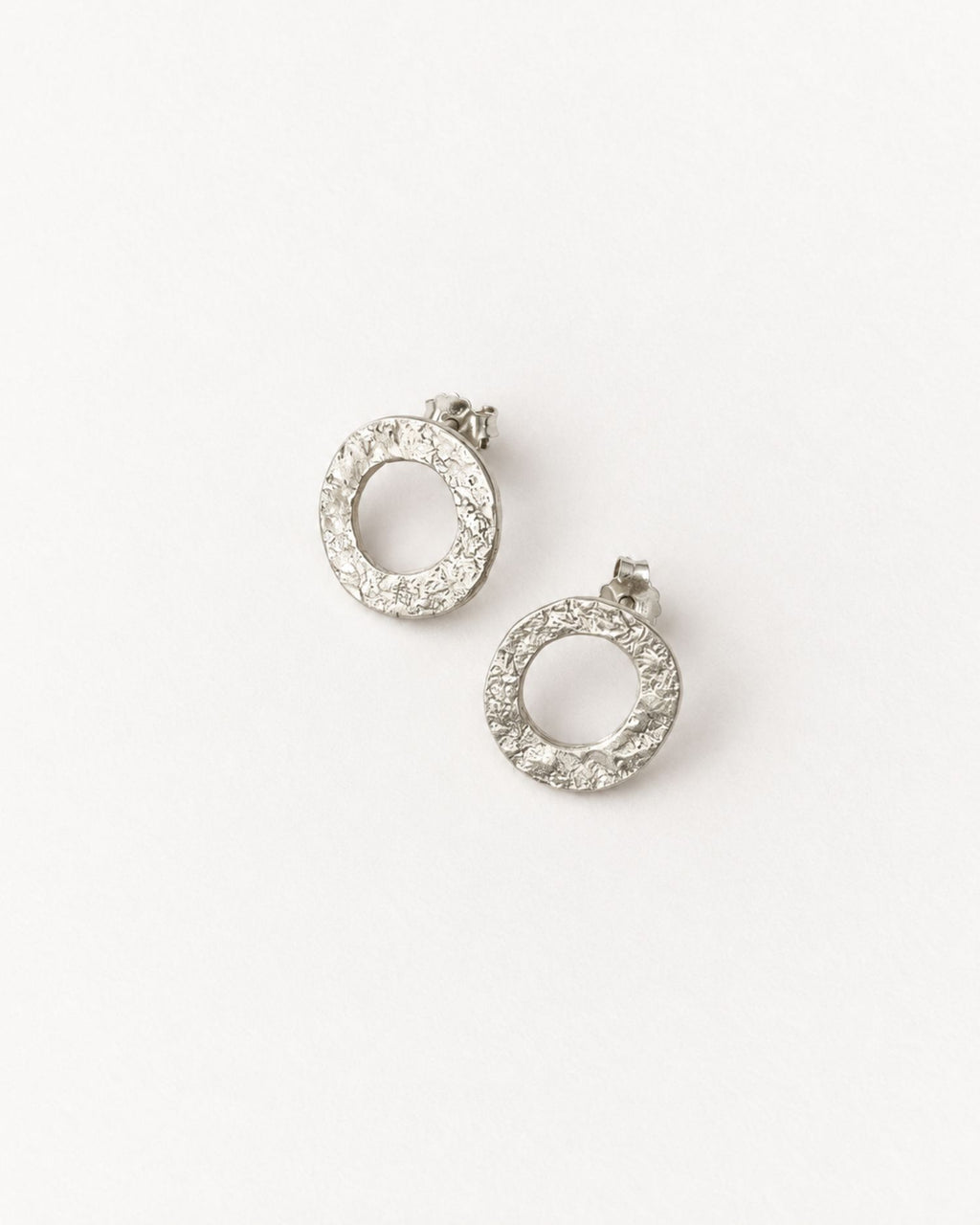 Silver lunar textured hoop earrings on a solid white background