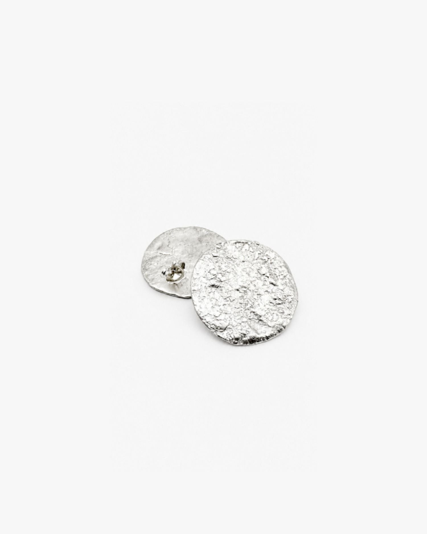 Silver round textured earring on a white background