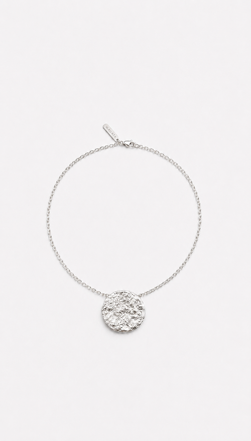 Silver chain necklace with a round moon textured pendant on a white background