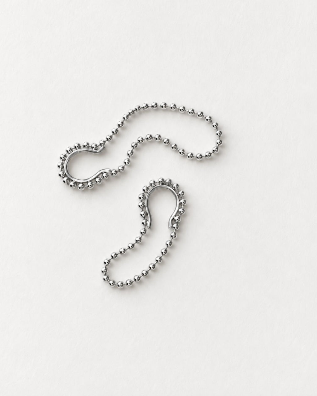 A pair of silver hoop earrings with a ball-chain outer edge, displayed on a clean white background.