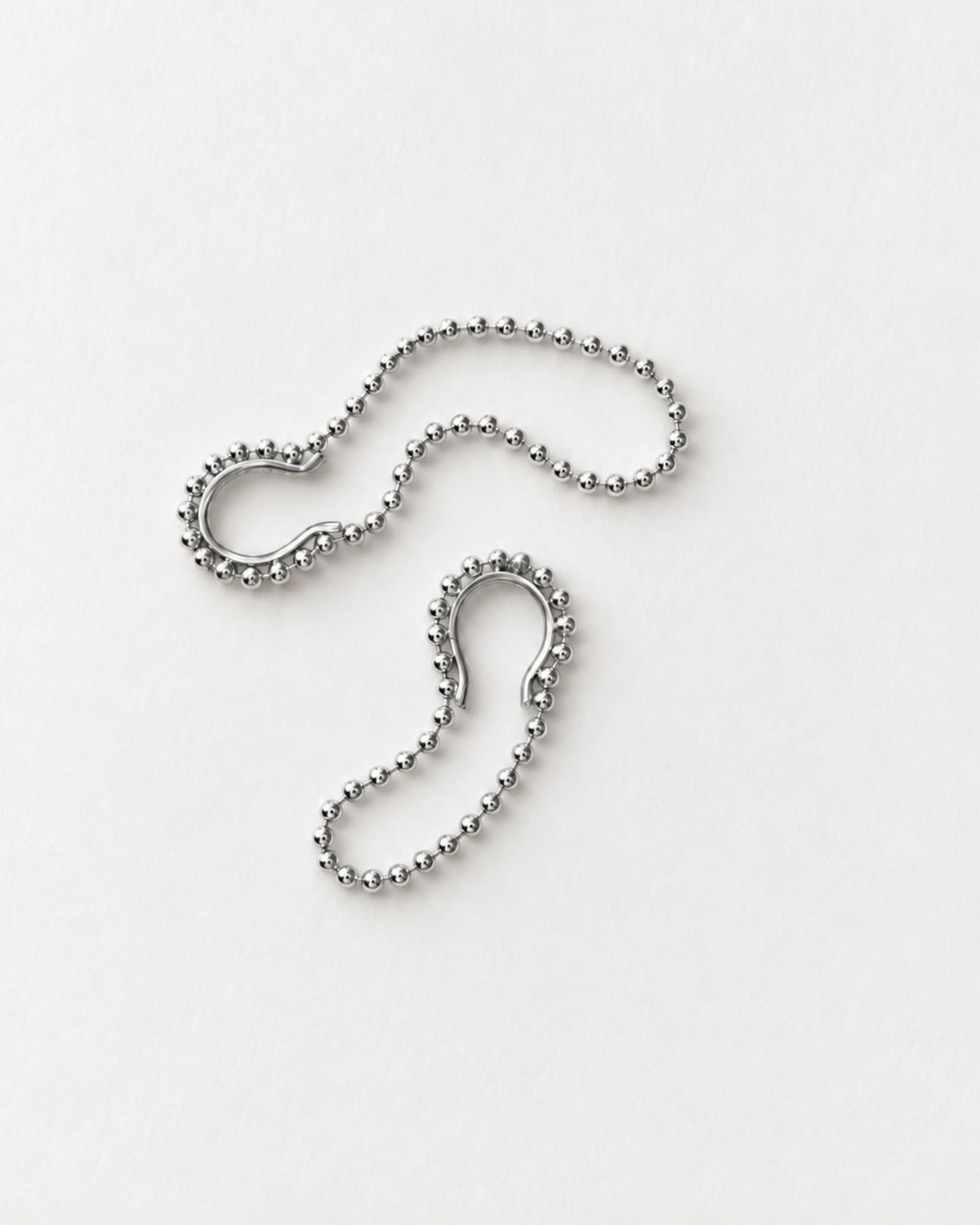 A pair of silver hoop earrings with a ball-chain outer edge, displayed on a clean white background.