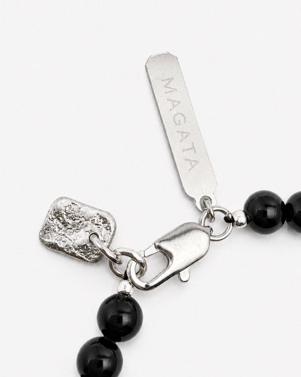 Black beaded bracelet with silver clasp and charm on a white background