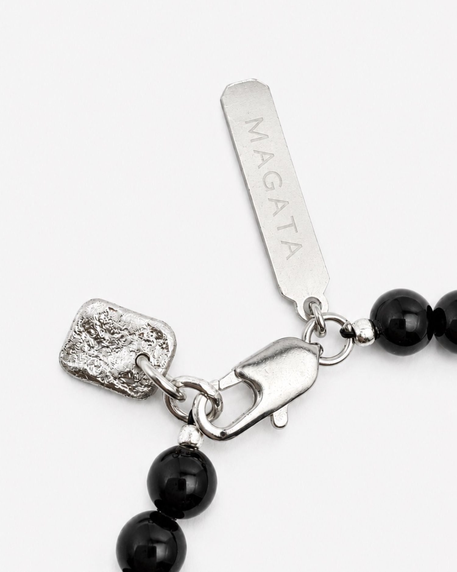 Black beaded bracelet with silver clasp and charm on a white background