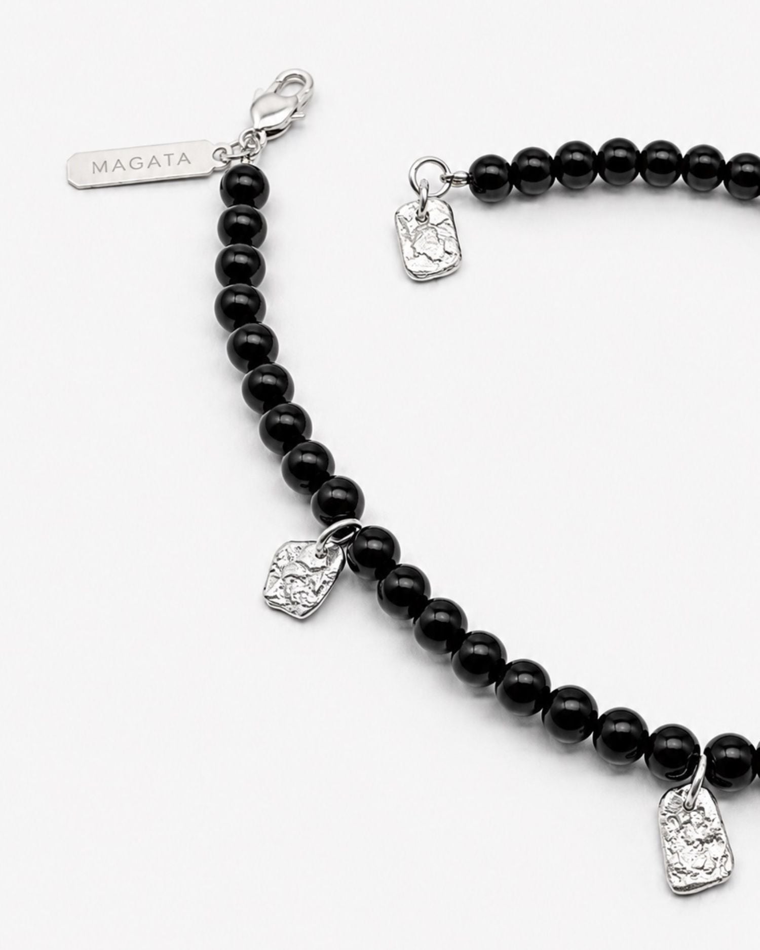 Black beaded bracelet with silver charms on a white background