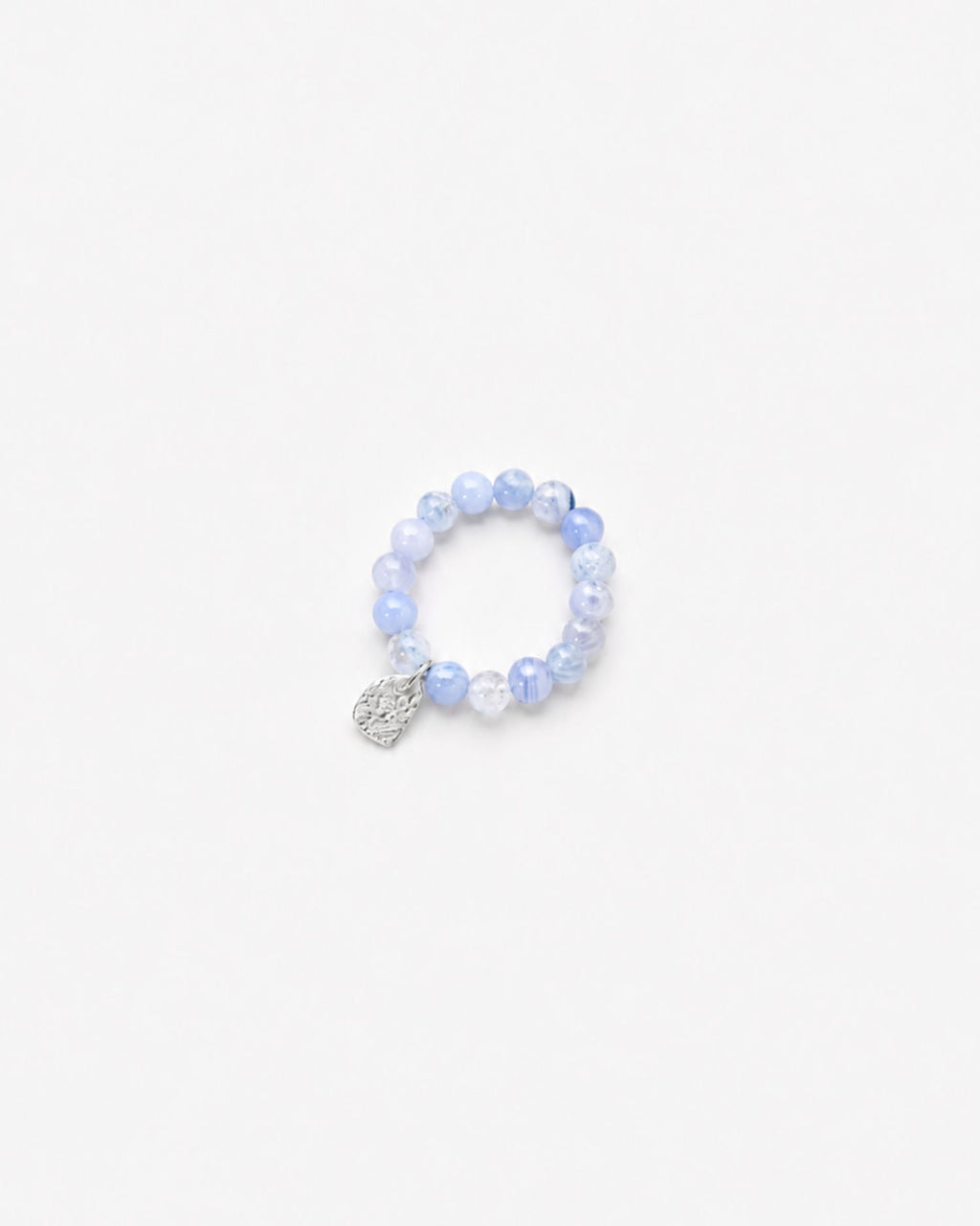 Beaded blue chalcedony ring with a textured silver charm on a white background