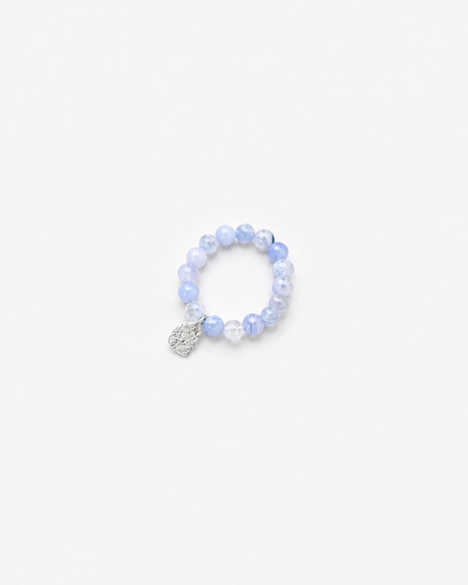 Beaded blue chalcedony ring with a textured silver charm on a white background