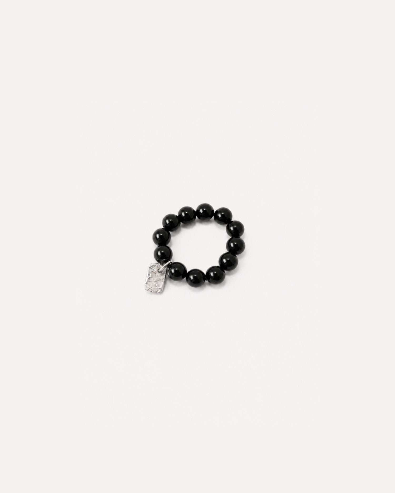 Beaded black onyx ring with a textured silver charm on a white background