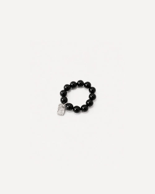 Beaded black onyx ring with a textured silver charm on a white background