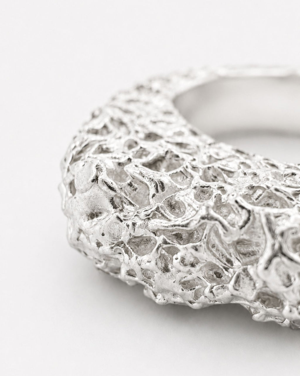 Silver ring with lava texture design on a white background