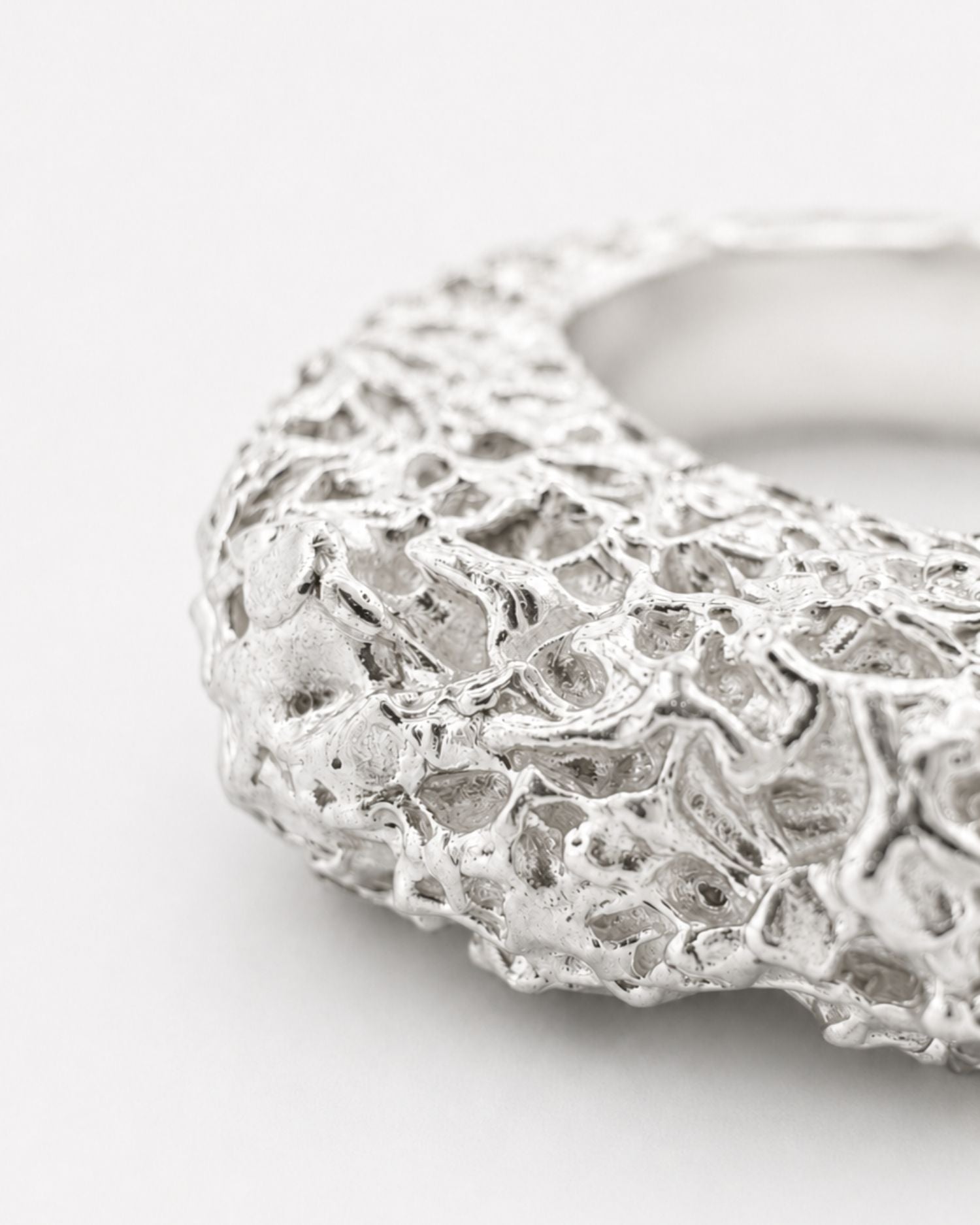 Silver ring with lava texture design on a white background