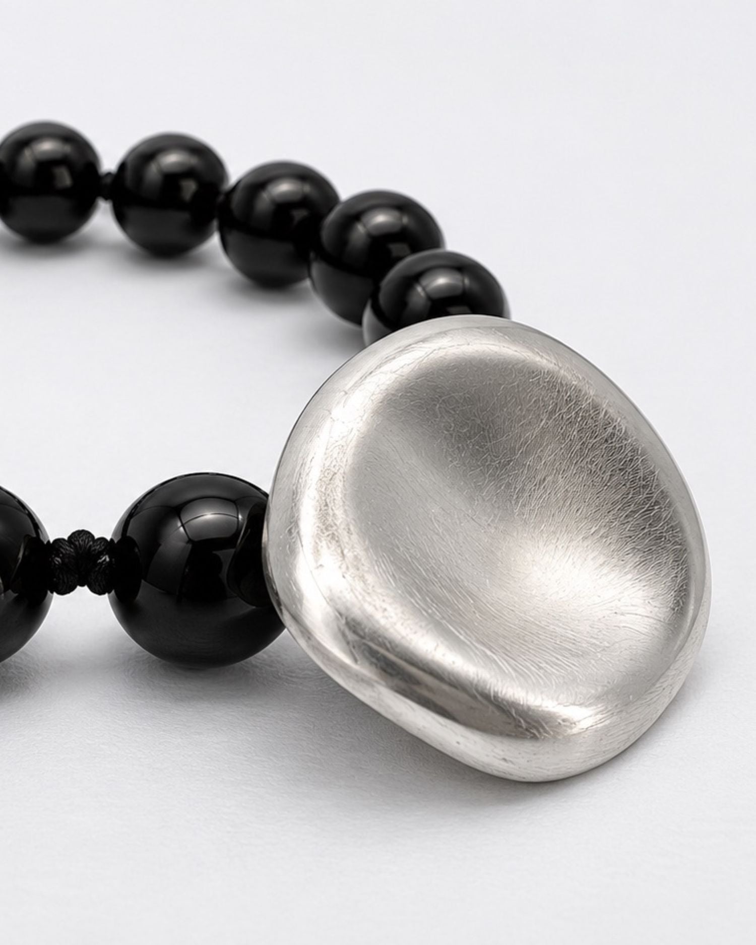 Black onyx  beaded bracelet with a large silver disc clasp on a light gray background